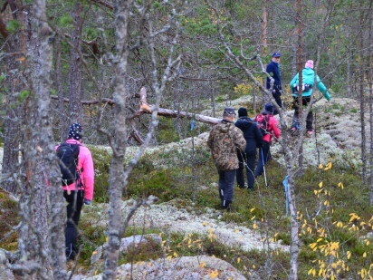 Vandrare i färglada kläder och ryggsäckar går över lavabevuxna bergknallar.