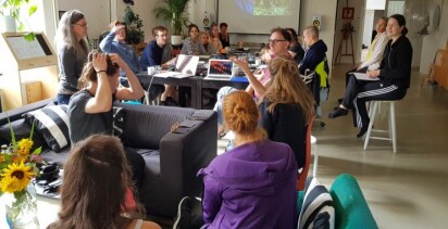 En grupp människor sitter avslappande i soffor och runt bord och diskuterar.