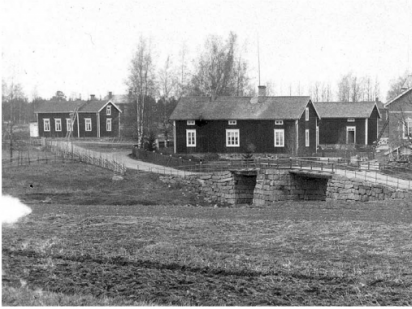 Vy över stenbro och fyra byggnader i svartvitt