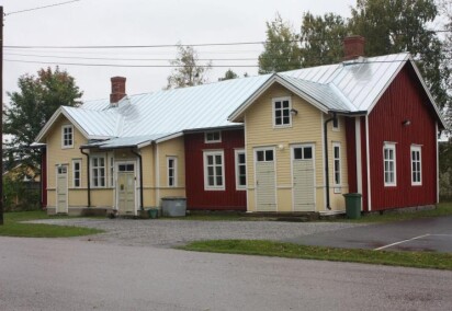 En röd och gul äldre byggnad i två våningar med fyra ingångar