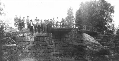 Stenbro med broräck och en samling män som poserar