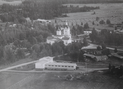Svartvitt flygfoto över Köpings skola, Malax kyrka och landskapet med höstörar