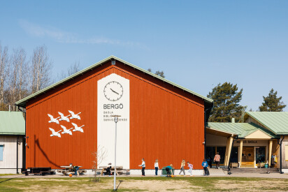 Bergö skola med en röd fasad med en stor klocka och en dekoration med sex flygande vita svanar.