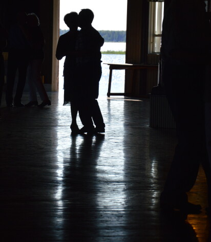 Pariskunta tanssii. Taustalla näkyy merta avoimesta ovesta.